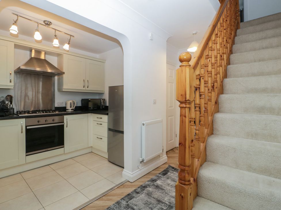 A kitchen with appliances and staircase at 42 Ynys Y Nos in Glynneath