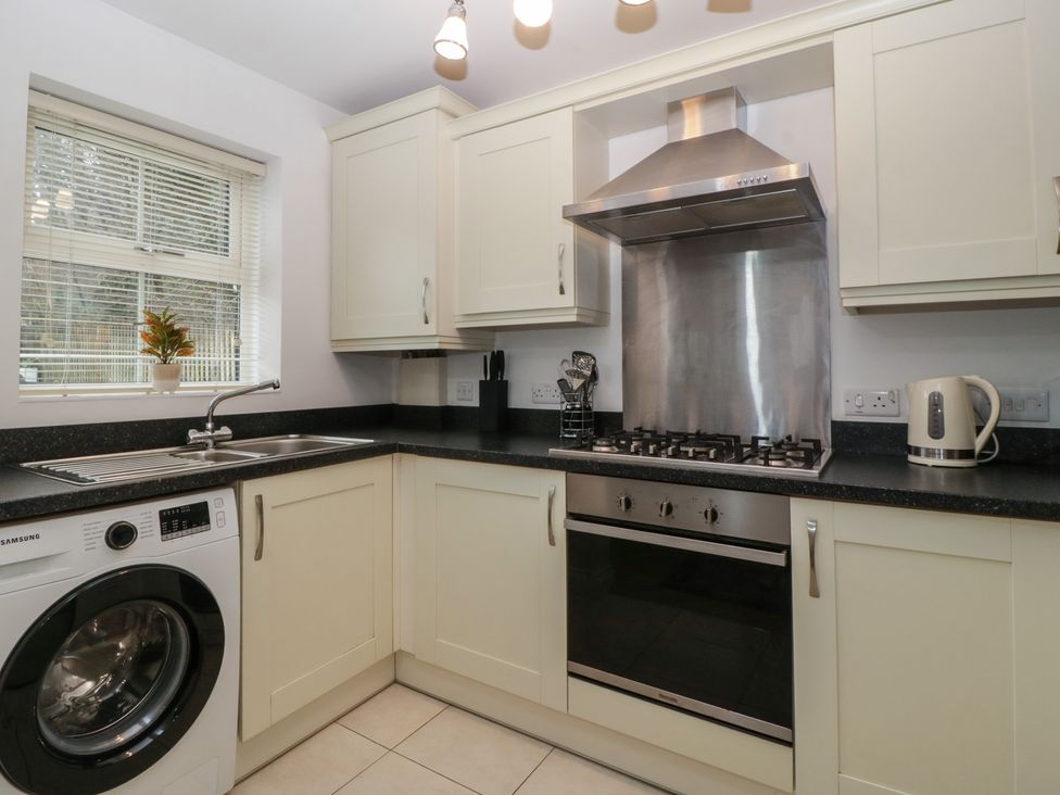 A kitchen with a stove and washing machine at 42 Ynys Y Nos in Glynneath