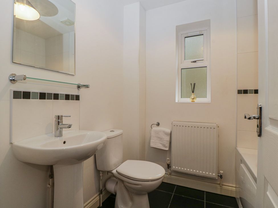 A bathroom with a sink, toilet, and mirror at 42 Ynys Y Nos in Glynneath
