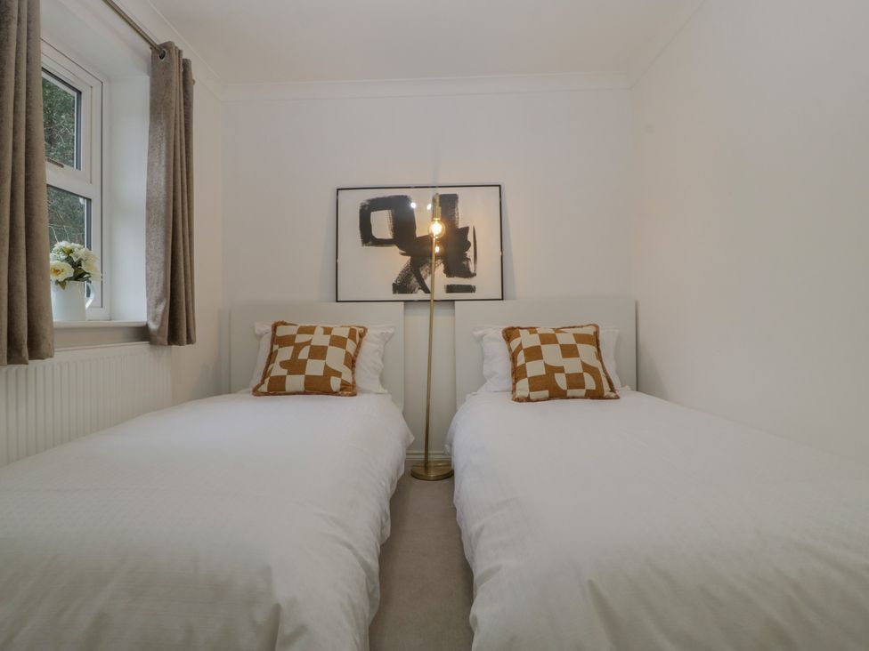 A bedroom with two beds and a lamp at 42 Ynys Y Nos Glynneath