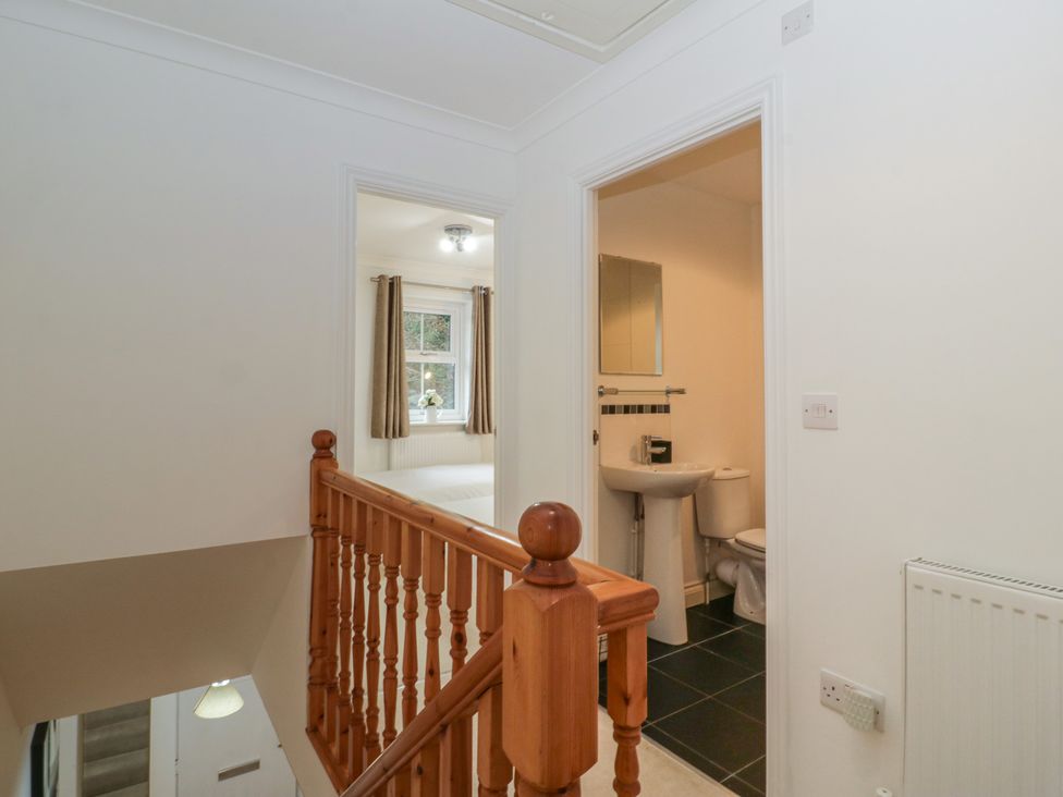 A hallway with a staircase leading to a toilet and sink at 42 Ynys Y Nos in Glynneath