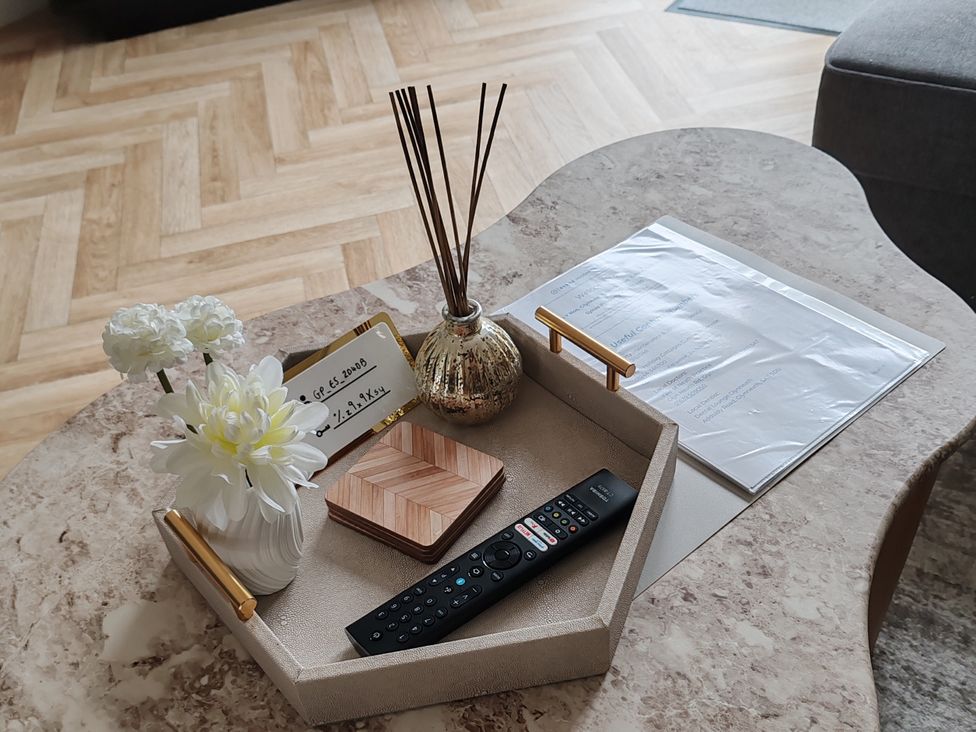 A coffee table with flowers, a remote control, and a note card at 42 Ynys Y Nos in Glynneath