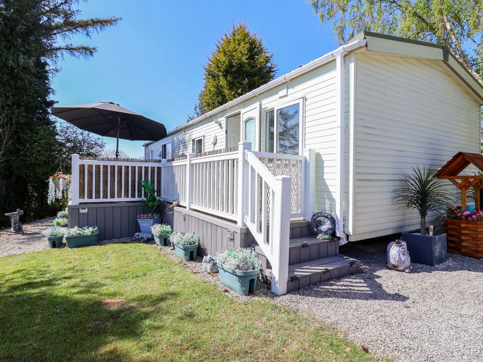 A mobile home with a deck and flower pots at Grosvenor 10 in Llanarmon-Yn-Ial