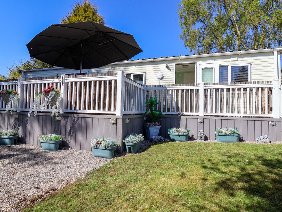 A caravan with a deck and umbrella at Grosvenor 10 Llanarmon-Yn-Ial