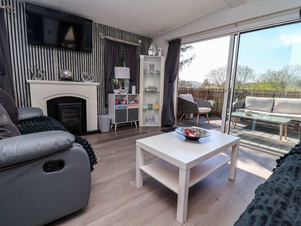 A living room with a fireplace and television at Grosvenor 10 in Llanarmon-Yn-Ial