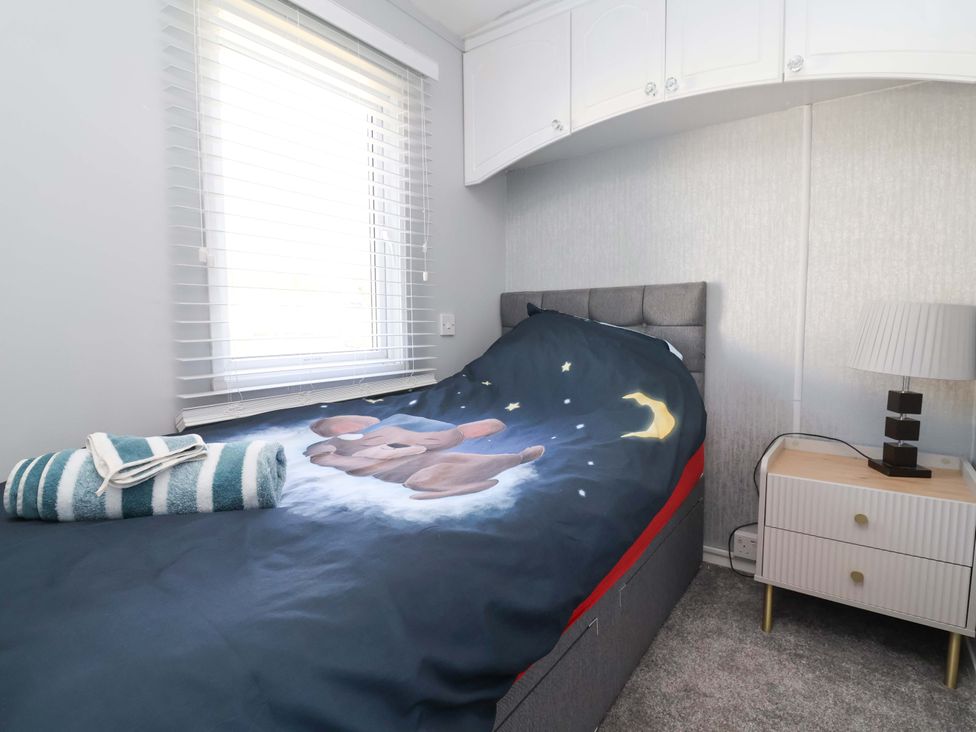 A bedroom with a bed and patterned blanket at Grosvenor 10 in Llanarmon-Yn-Ial