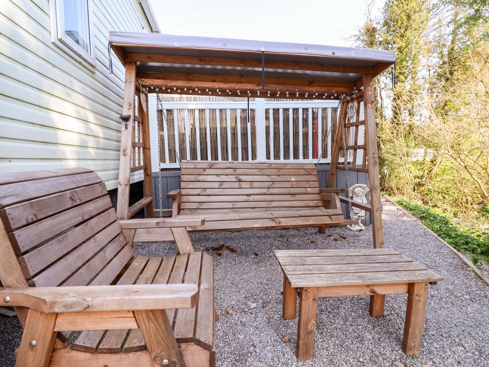 An outdoor seating area with a swing bench and a small table at Grosvenor 10 in Llanarmon-Yn-Ial