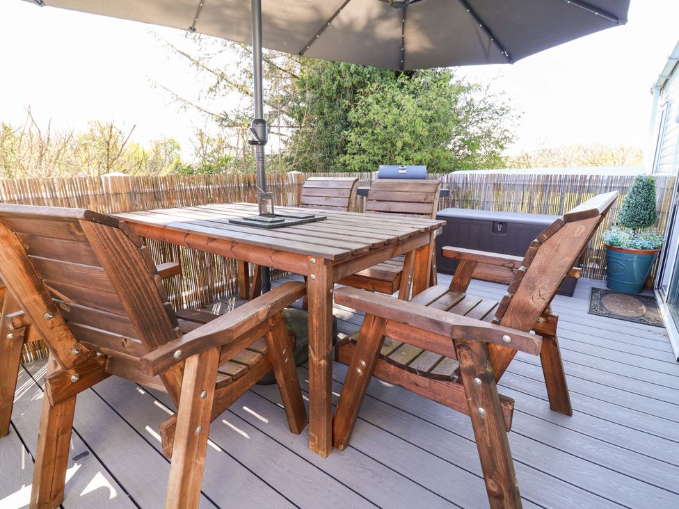 An outdoor dining area with wooden table and chairs at Grosvenor 10 in Llanarmon-Yn-Ial