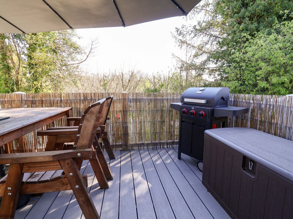 An outdoor seating area with a grill and wooden table at Grosvenor 10 in Llanarmon-Yn-Ial