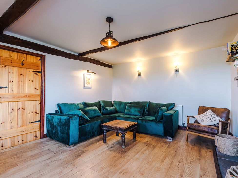 A living room with a green sofa and wooden coffee table at Landskill Farm in Preston