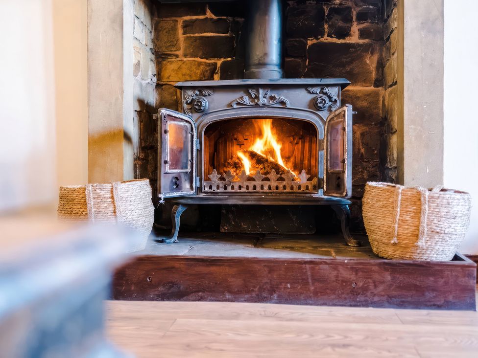 A wood stove with flames in a living room at Landskill Farm in Preston