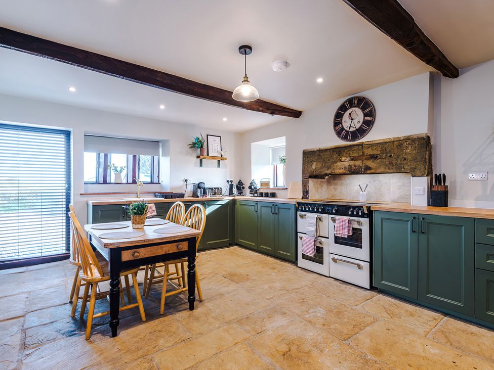 A kitchen with cabinets and a dining table at Landskill Farm Preston