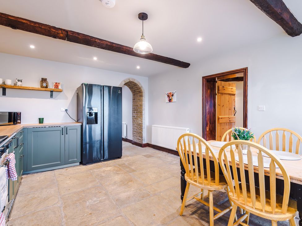 A kitchen with refrigerator, table, and chairs at Landskill Farm Preston