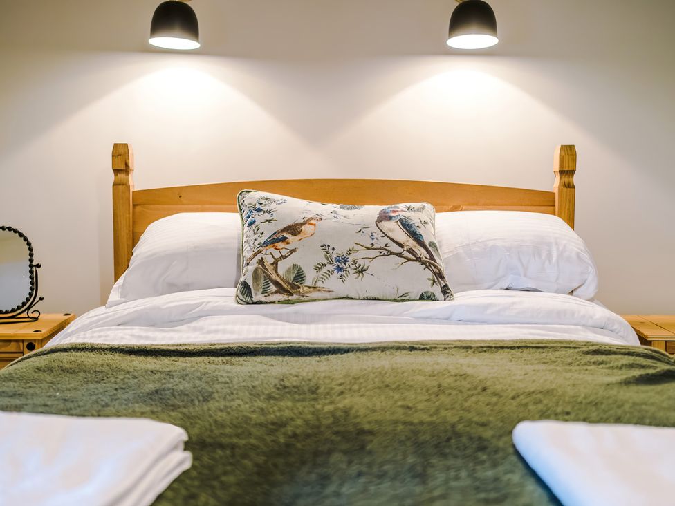 A bed with a green blanket and decorative pillow at Landskill Farm Preston
