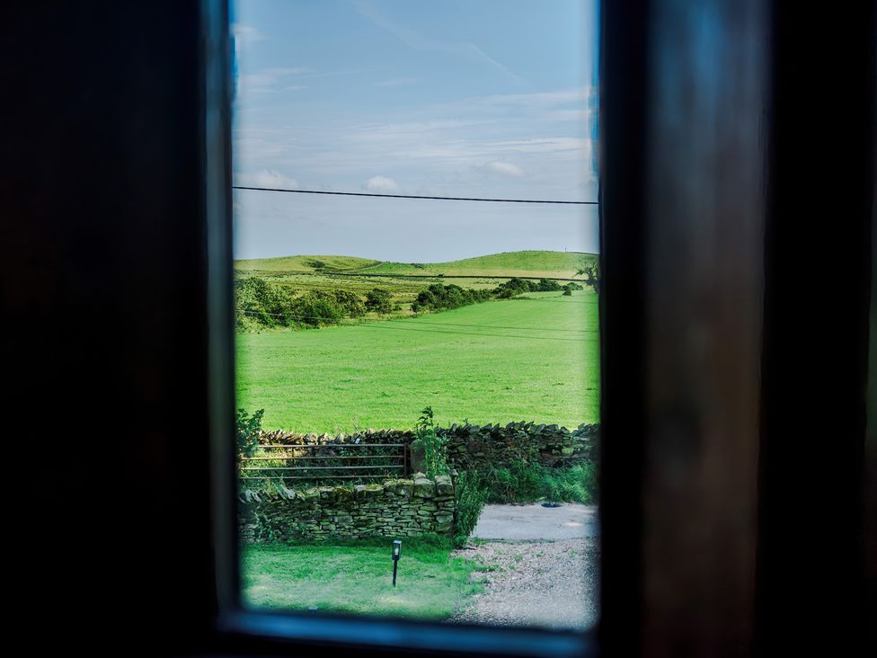 A view of a green field and hills from a window at Landskill Farm in Preston