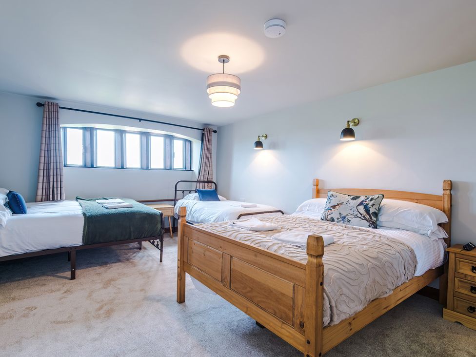 A bedroom with three beds and a window at Landskill Farm in Preston