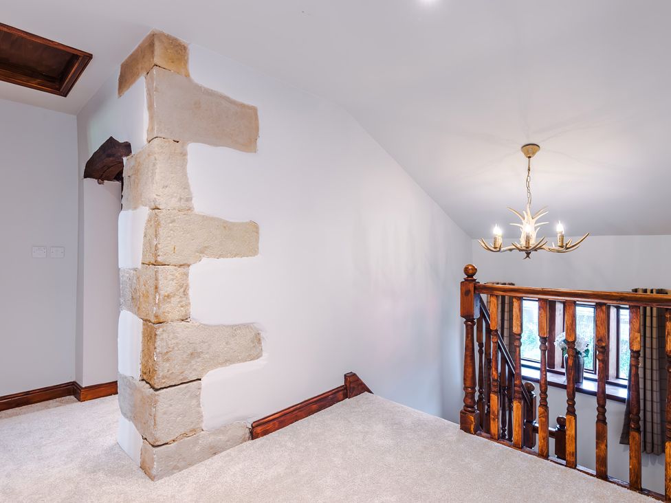 A landing with a staircase and chandelier at Landskill Farm in Preston