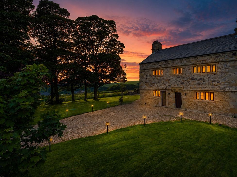 A house with lit windows and surrounding trees at Landskill Farm in Preston