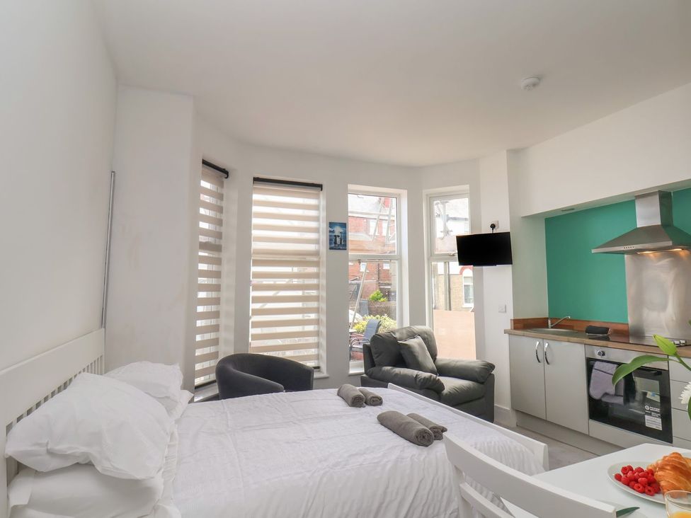 A bedroom with a bed, sofa, and kitchen unit at Frankie’s Seaview 1 in Bridlington