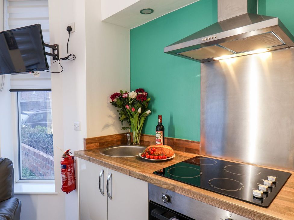 A kitchen with a sink, cooktop, and floral arrangement at Frankie’s Seaview 1 in Bridlington