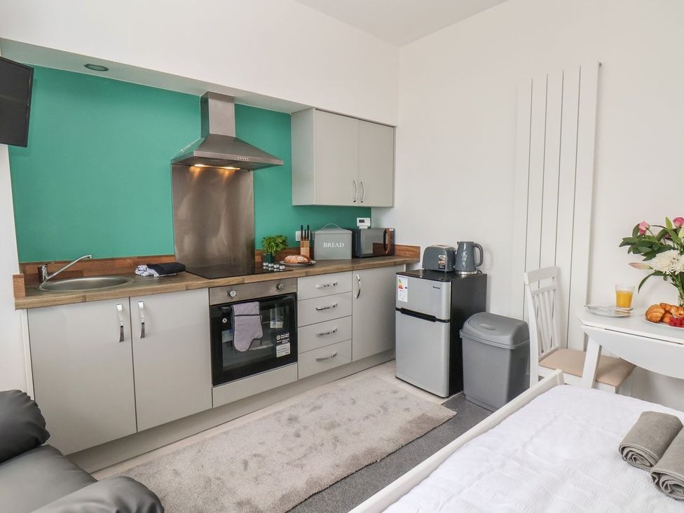 A kitchen with a fridge, stove and table at Frankie’s Seaview 1 in Bridlington