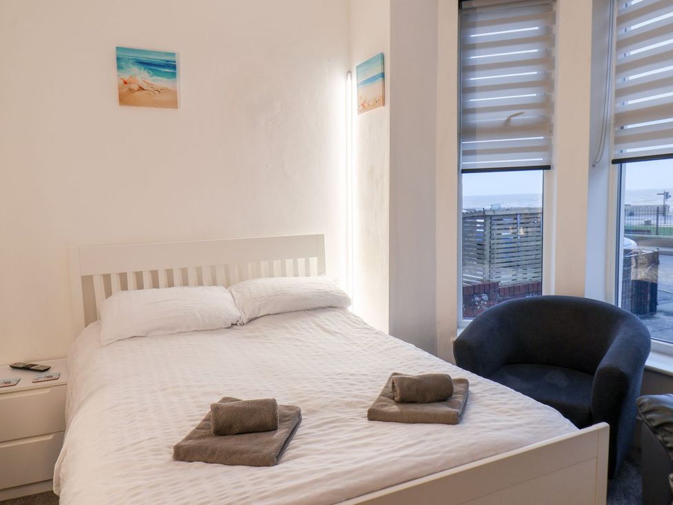 A bedroom with a bed and armchair at Frankie’s Seaview 1 Bridlington
