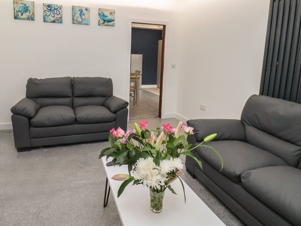 A living room with two sofas and a table with flowers at Frankie’s Seaview 2 in Bridlington