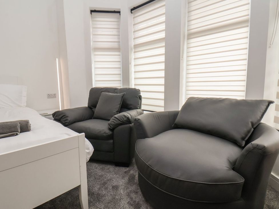 A bedroom with a bed and two armchairs at Frankie’s Seaview 4 in Bridlington