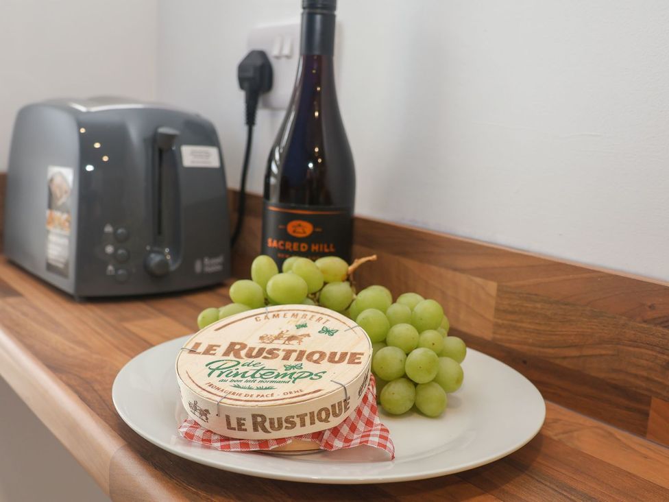 A kitchen countertop with a toaster, bottle of wine, grapes, and cheese at Frankie’s Seaview 4 in Bridlington