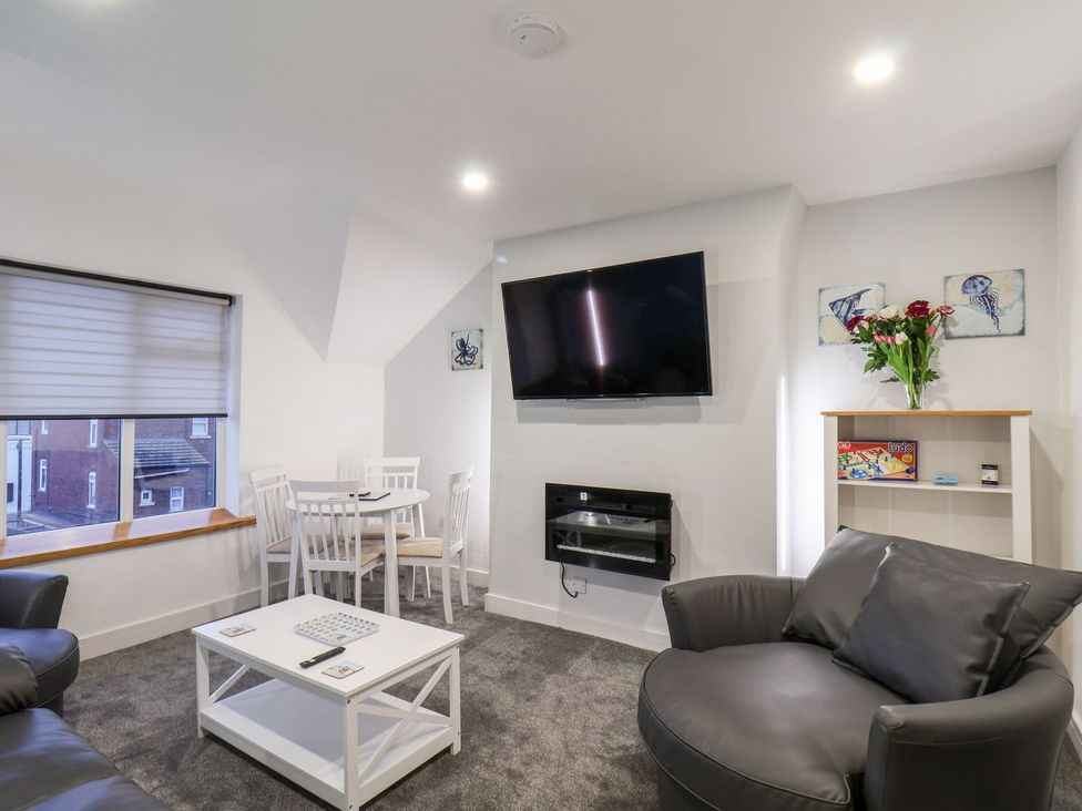 A living room with a sofa, coffee table, and television at Frankie’s Seaview 5 in Bridlington