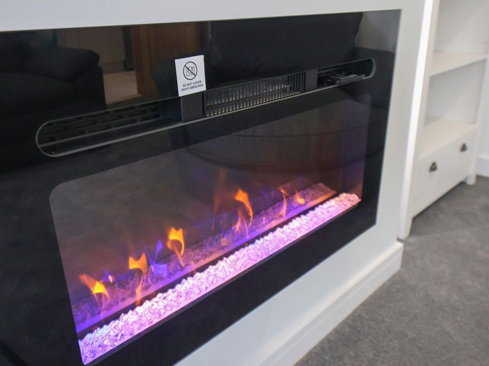 An electric fireplace with decorative stones at Frankie’s Seaview 5 in Bridlington