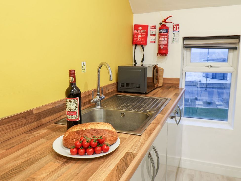 A kitchen with a sink, bottle of wine, bread and tomatoes at Frankie’s Seaview 5 in Bridlington