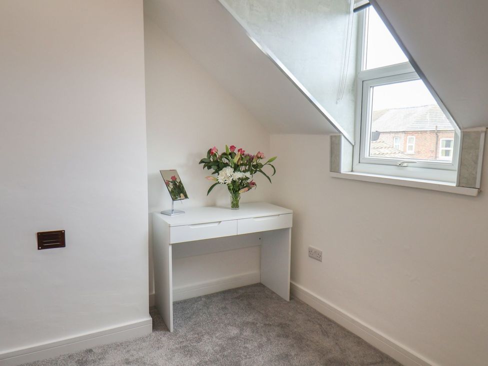 A bedroom with a desk and flowers at Frankie’s Seaview 5 in Bridlington