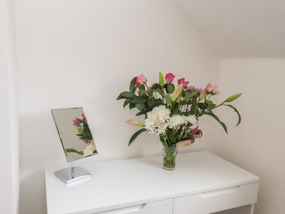 A vase with flowers and a mirror on a dresser at Frankie’s Seaview 5 in Bridlington