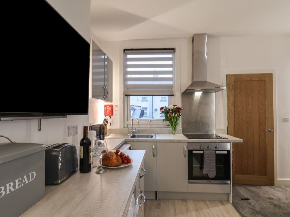 A kitchen with a wine bottle and flowers on the counter at Frankie’s Seaview 3 in Bridlington
