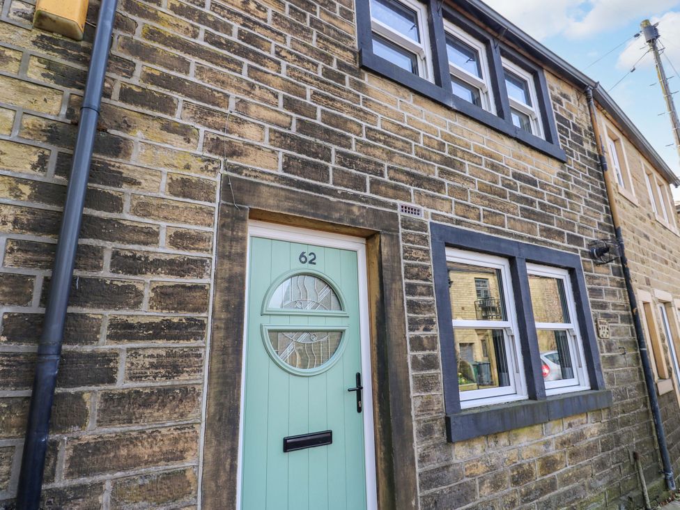 A front entrance with a green door and windows at Milburn Cottage in Keighley