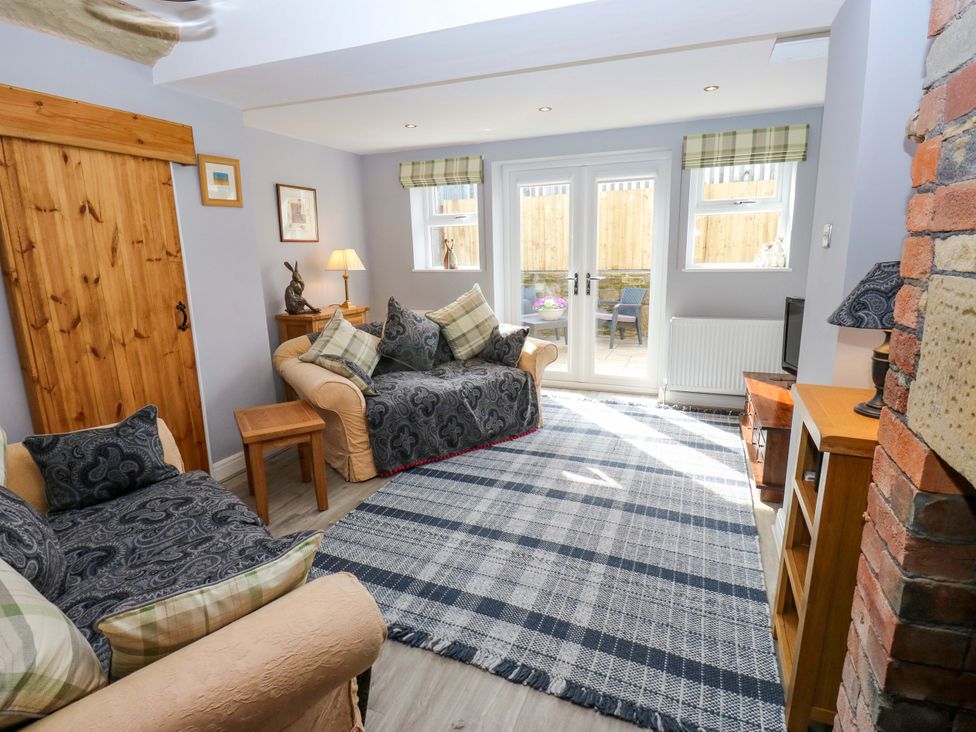 A living room with a couch and armchair at Milburn Cottage in Keighley