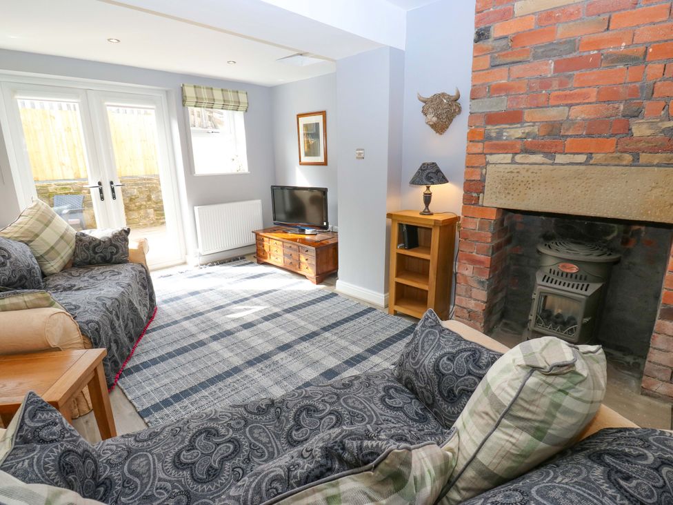 A living room with a television and a fireplace at Milburn Cottage Keighley