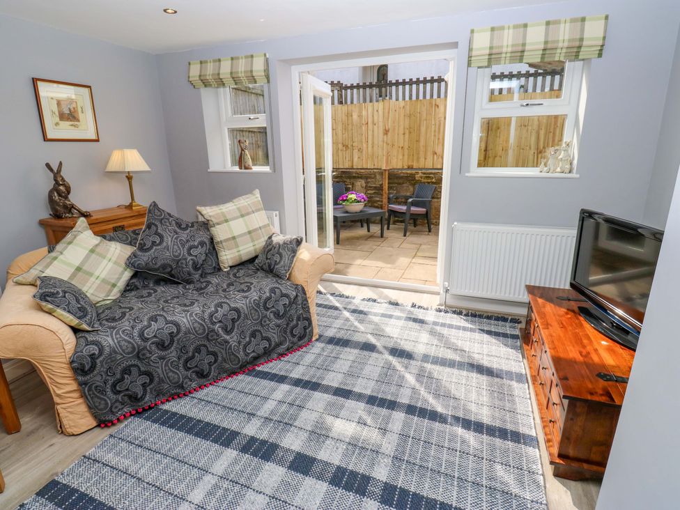 A living room with a sofa and television at Milburn Cottage in Keighley