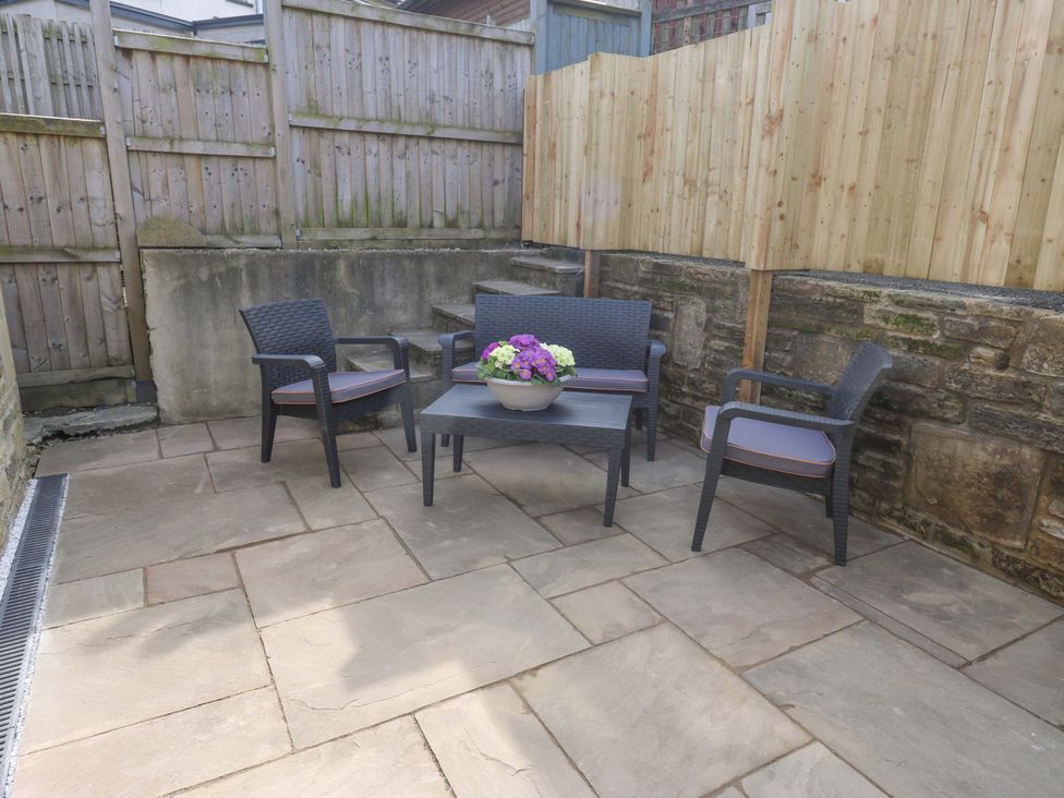 A garden with furniture and a flower pot at Milburn Cottage Keighley