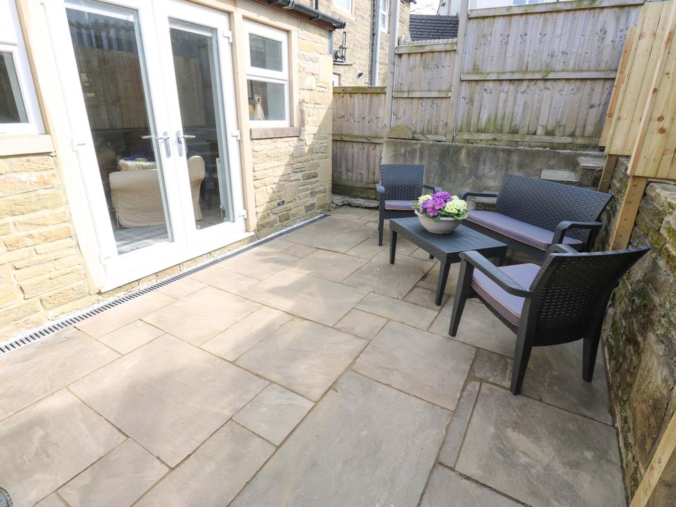 An outdoor seating area with a table and chairs at Milburn Cottage in Keighley