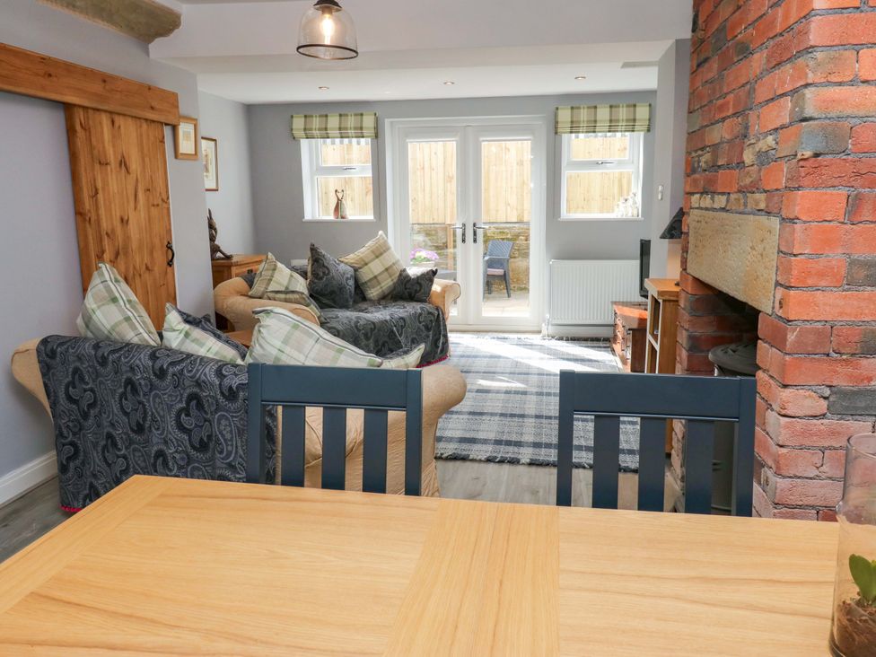 A living room with a sofa, table and fireplace at Milburn Cottage in Keighley