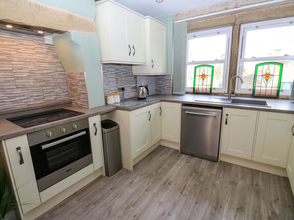 A kitchen with a stove, sink and cabinets at Milburn Cottage in Keighley