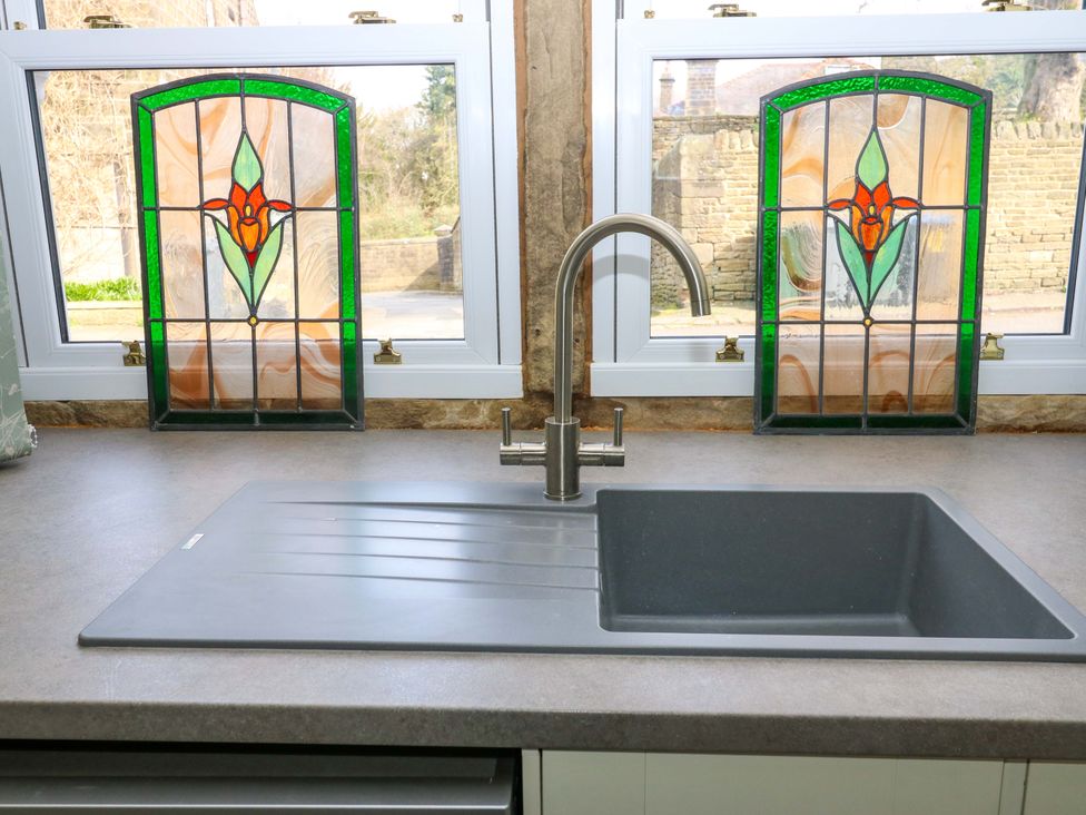 A kitchen with a sink and stained glass windows at Milburn Cottage in Keighley