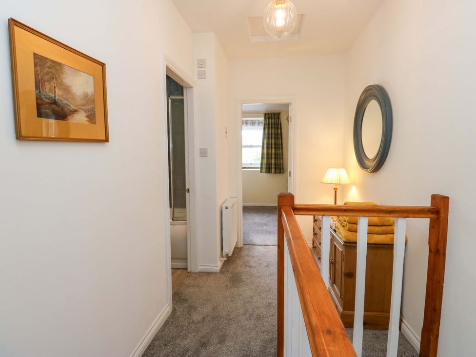 A hallway with a painting and a mirror at Milburn Cottage in Keighley
