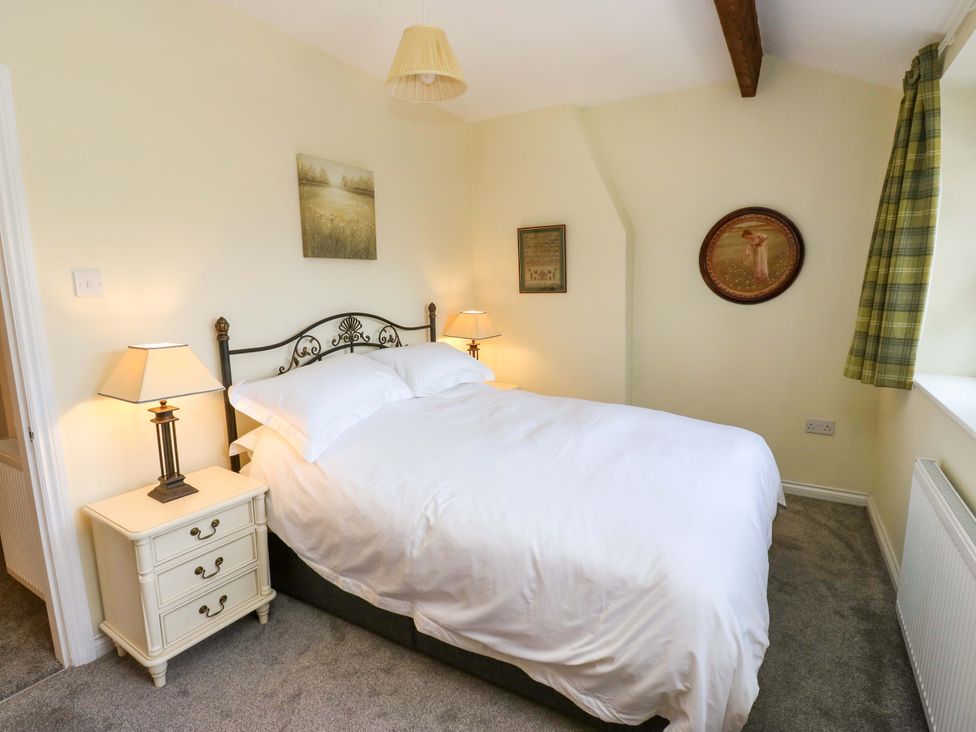 A bedroom with a bed and bedside table at Milburn Cottage in Keighley