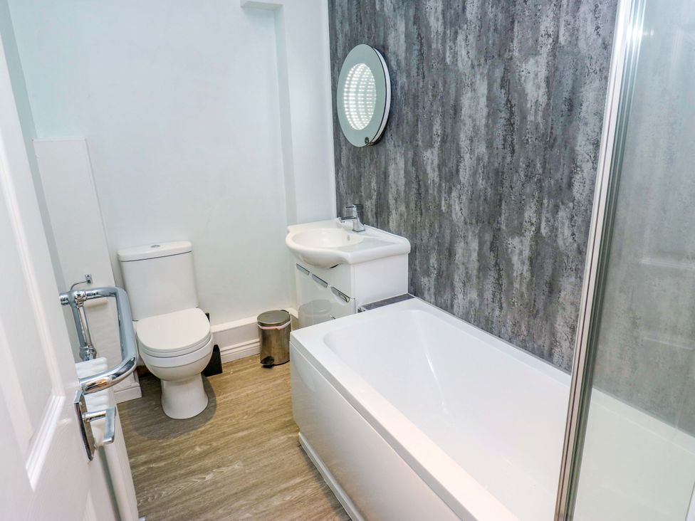 A bathroom with a sink, toilet, and bathtub at Milburn Cottage in Keighley
