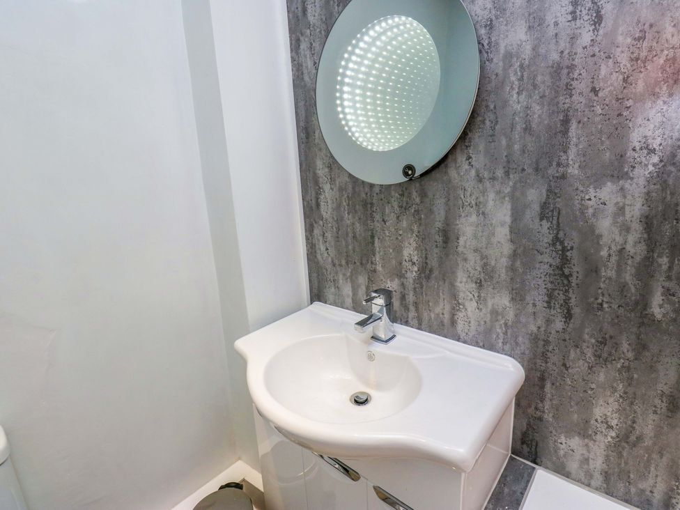 A bathroom with a sink and mirror at Milburn Cottage in Keighley