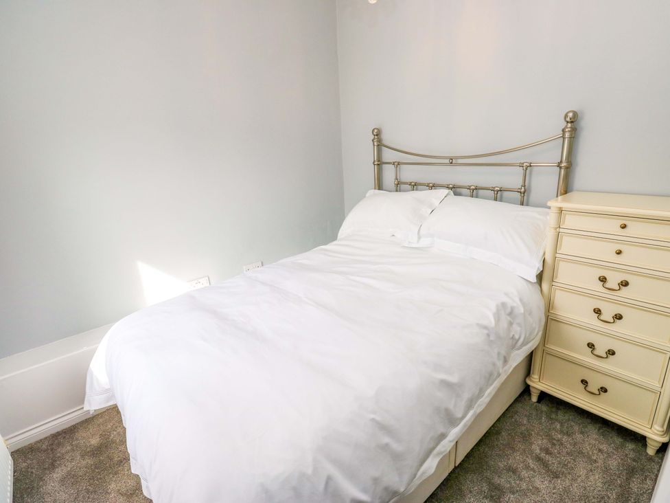 A bedroom with a bed and nightstand at Milburn Cottage in Keighley