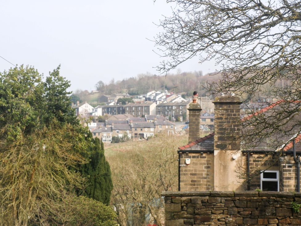 A view of houses and trees on a hill at Milburn Cottage in Keighley